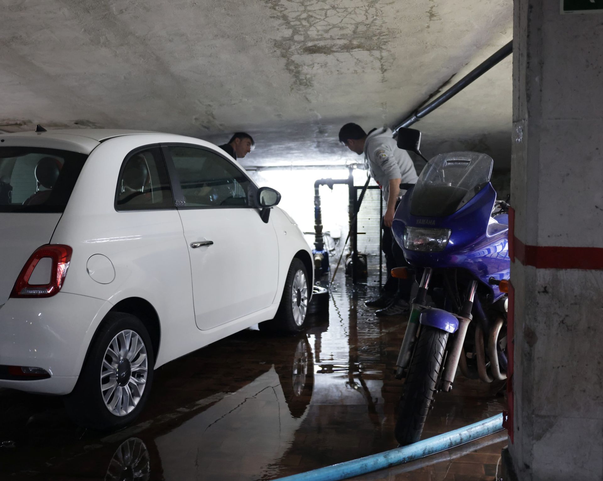Vecinos de la calle Acibelas 13 comprueban los daños que ha provocado el agua en sus garajes.